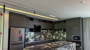 Una cocina moderna con una isla de mármol, electrodomésticos integrados y un televisor de pantalla plana.