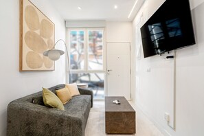 Ein modernes Wohnzimmer mit grauem Sofa, einem Couchtisch und einem flachbildfernseher an der Wand.