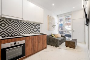 Eine moderne Küche mit Backofen und ein graues Sofa im Wohnbereich.