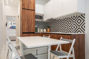 Eine kleine Küche mit Mikrowelle, Holzschränken und einer gemusterten Spritzschutzwand.