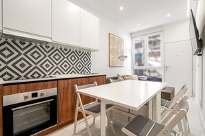 Eine moderne Küche mit Backofen, einem Esstisch mit Stühlen und einer Wandfliesenverkleidung mit Muster.