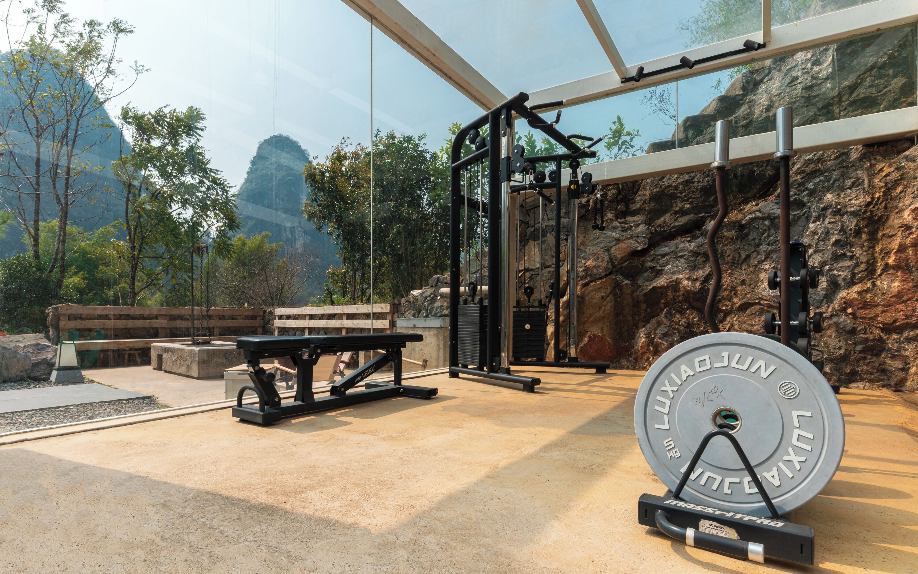 An outdoor gym with exercise equipment, a bench, and a weight plate.