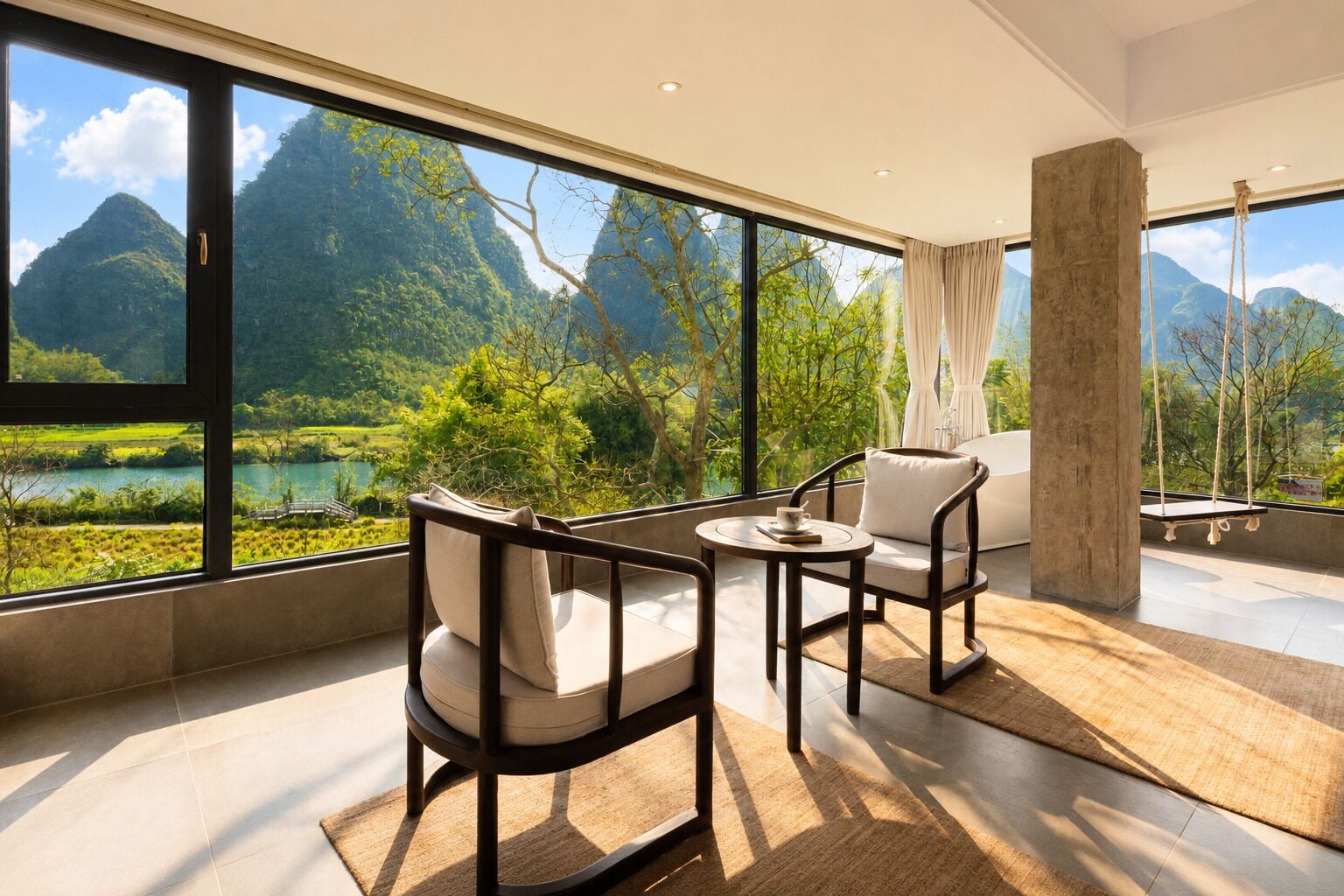 A modern room with large windows, a swing, and a view of mountains and greenery.
