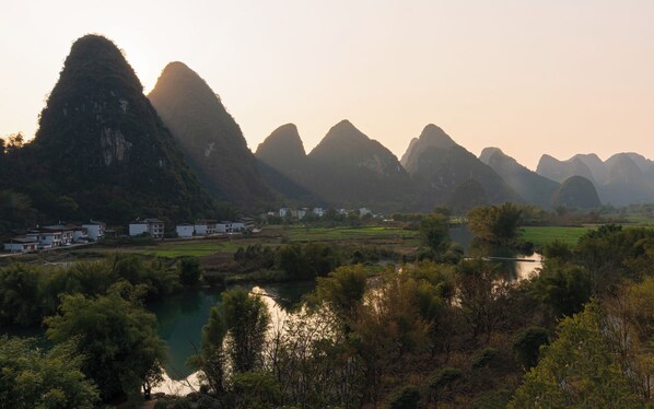 A mountainous landscape with a river and buildings in the foreground. - The Dragon’s Rest Sanctuary - Yulong River Branch (Guilin)