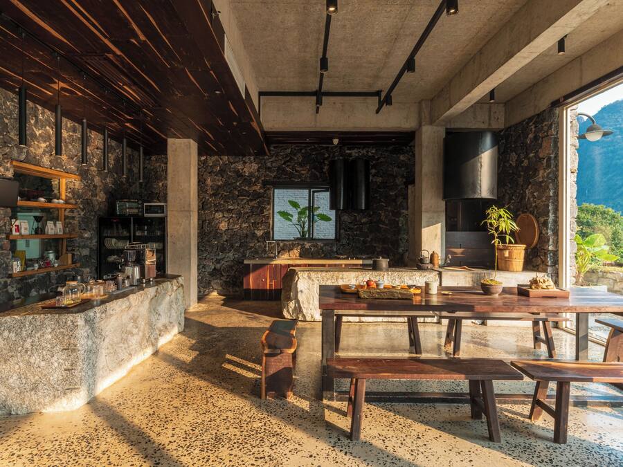 Una cocina moderna con paredes de piedra, un ventanal grande y un comedor con mobiliario de madera.