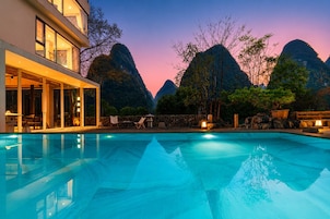 Una piscina con vistas a montañas al atardecer.