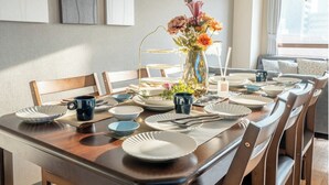 A dining table set with plates, bowls, and a vase of flowers. - Akitsu 703 Kyocera Dome 10 min walk Dotonbori Kansai Airport Osaka Castle Kaiyukan USJ 1 transfer Family friendly Free parking 15 (大阪府大阪市西区境川１丁目)