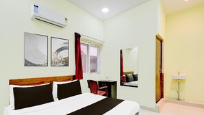 A hotel room with a bed, a desk, a chair, a window with curtains, a wall-mounted air conditioner, and a sink. - Super Hotel O Kota Railway Junction (Kota)
