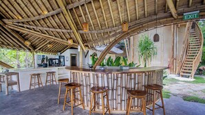 A bamboo-themed bar area with stools and a staircase.