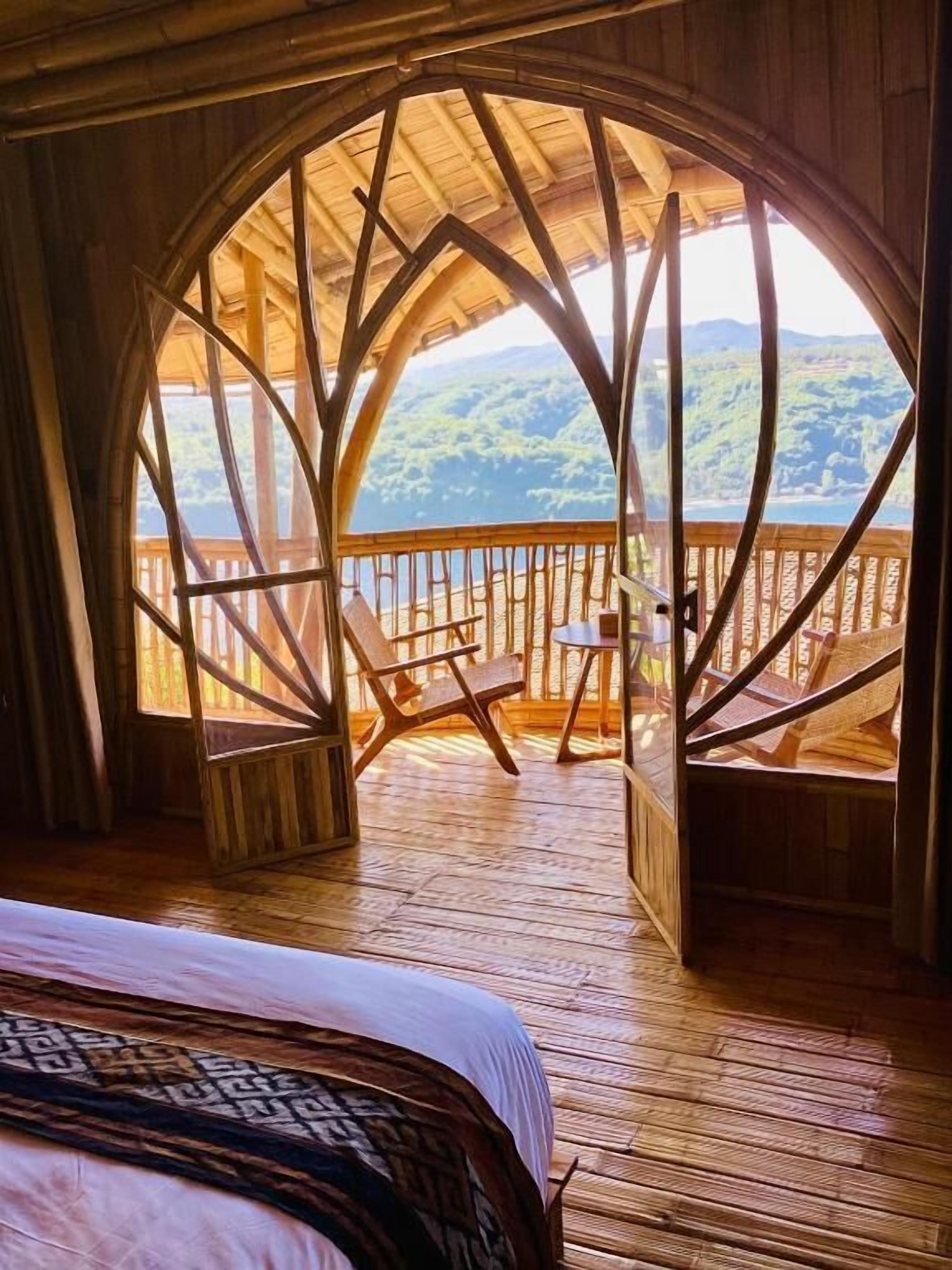Een houten chalet met een groot rondboogvenster dat uitkijkt op een bebost landschap.