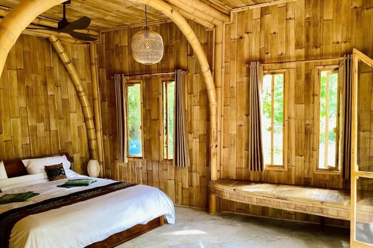 A room with a large bed, a bench, and large windows.