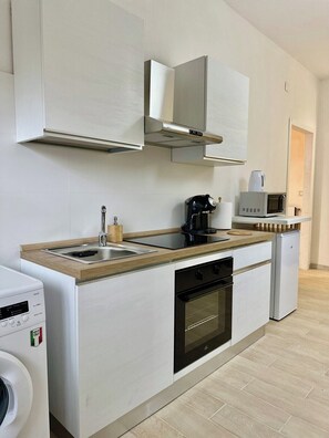 A modern kitchen with a built-in oven, a coffee machine, and a microwave. - Quiet Modern Apartment near Center | Free Street Parking (Oristano)