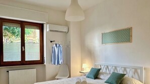 Un dormitorio con cama, una silla colgante, un radiador, aire acondicionado y una ventana con persianas.