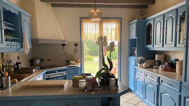 A kitchen with blue cabinets, a central island, and a view of greenery outside. - Cozy 1-bedroom house in amazing Villebon sur Yvette with AC (Villebon sur Yvette)