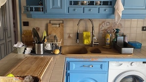 A kitchen with blue cabinets, a washing machine, and a sink with a yellow towel hanging on the faucet. - Cozy 1-bedroom house in amazing Villebon sur Yvette with AC (Villebon sur Yvette)