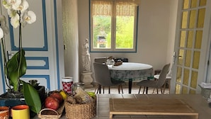 A kitchen with blue cabinets, a clock, a dining table with chairs, and a window with curtains. - Cozy 1-bedroom house in amazing Villebon sur Yvette with AC (Villebon sur Yvette)