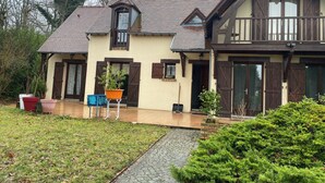 A two-story house with a sloped roof, wooden shutters, and a stone pathway leading to the entrance. - Cozy 1-bedroom house in amazing Villebon sur Yvette with AC (Villebon sur Yvette)