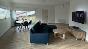 A modern living room with a sectional sofa, a round coffee table, and a TV mounted on the wall. - Atypical town house (Saint-Mariens)