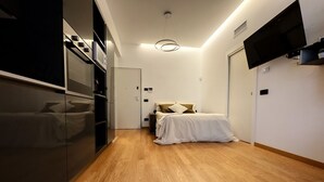 Quarto com cama, guarda-roupa, televisão e luz no teto.