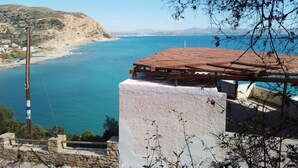 A coastal view with a white building and a wooden structure with a tiled roof overlooking the sea. - Loggia (Agia Galini)