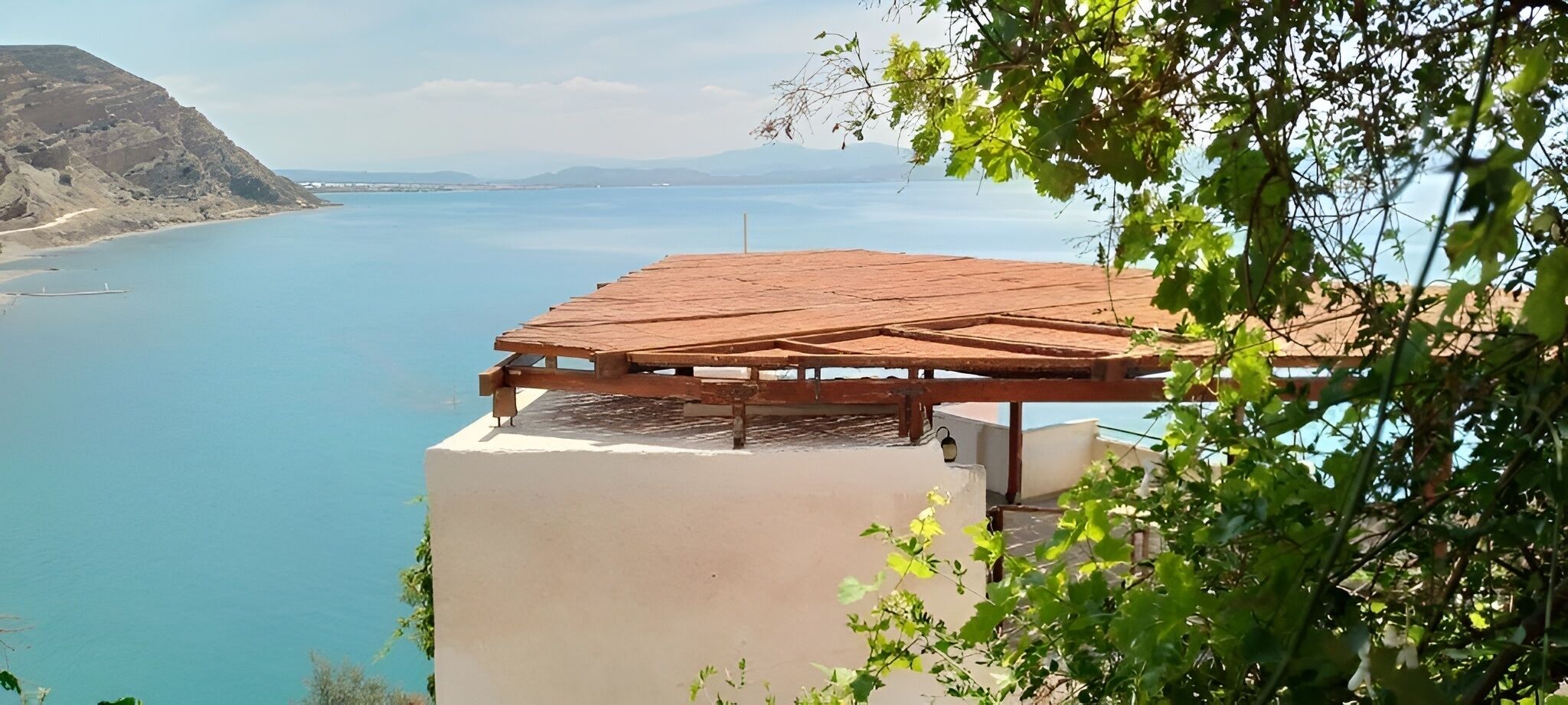 A high vantage point with a wooden deck overlooking a body of water and distant mountains.