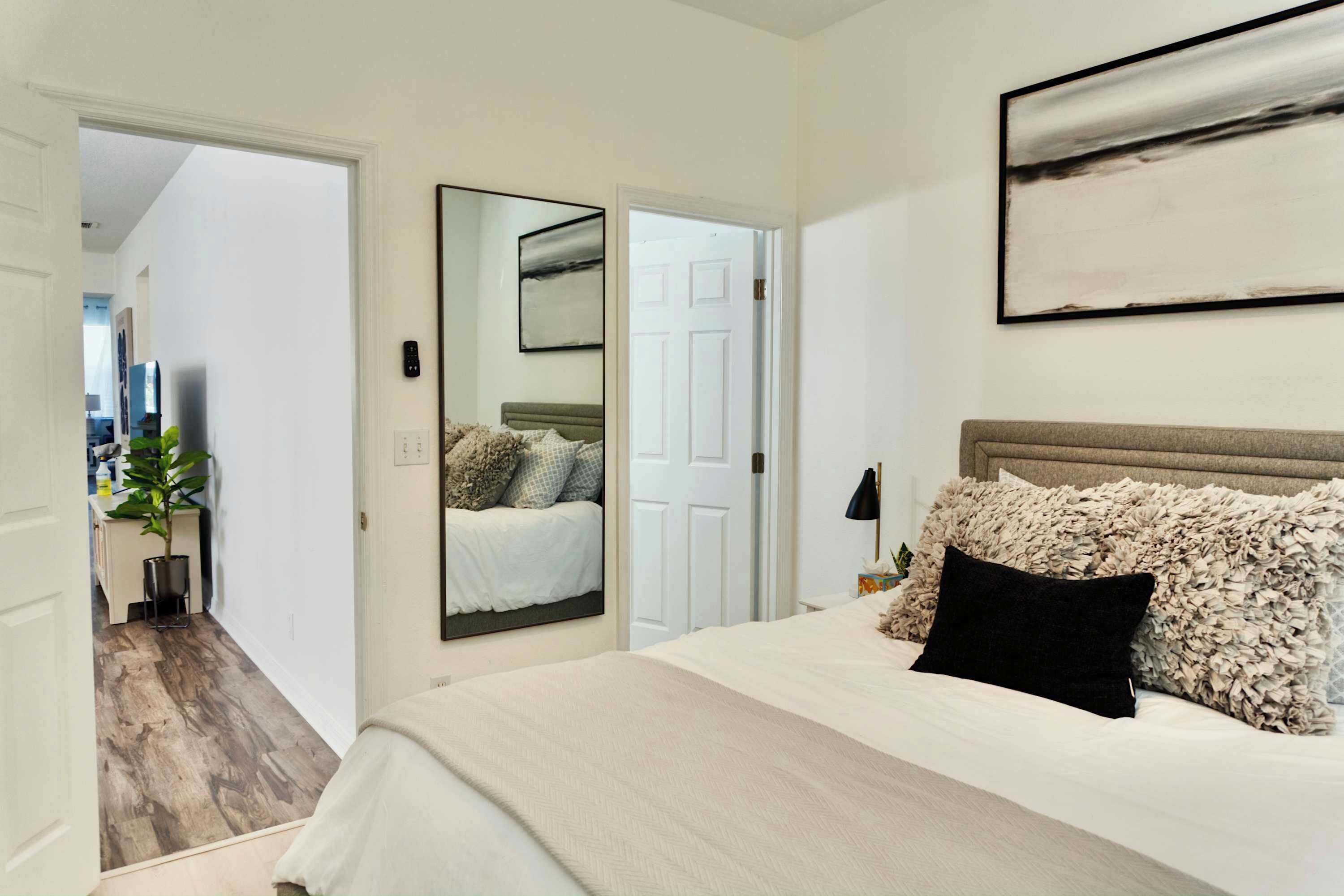 Un dormitorio con una cama grande, un espejo y una puerta que da a otra habitación.