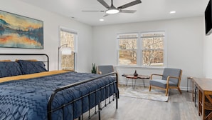 Une chambre moderne avec un lit, une chaise, un bureau et une grande fenêtre.