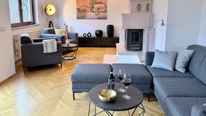 Un salon moderne avec un canapé, un fauteuil et une table basse, une cheminée et un tableau au mur.