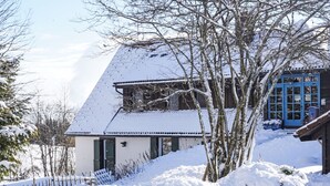 A snow-covered house with a sloped roof, a visible chimney, and a blue door. - Schwarzwaldhof mit Pool & Sauna by Interhome (Görwihl)