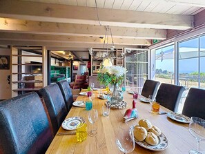 A dining area with a long wooden table, multiple chairs, and a view through large windows. - Schwarzwaldhof mit Pool & Sauna by Interhome (Görwihl)
