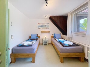 A room with two wooden beds, a nightstand with a lamp, a painting on the wall, and a window with a view. - Schwarzwaldhof mit Pool & Sauna by Interhome (Görwihl)