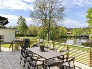 Una terraza con una mesa y sillas, con vista a un lago que incluye un puente y edificios al fondo.