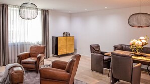 A modern living room with leather armchairs, a wooden coffee table, and a dining area with a chandelier. - Munich Finest Apartments Studio 1 by Interhome (Munich)