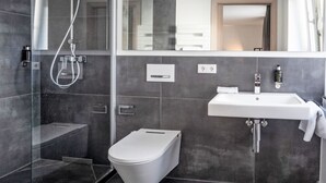 A modern bathroom with a glass-enclosed shower, a white toilet, and a large mirror above the sink. - Munich Finest Apartments Studio 1 by Interhome (Munich)