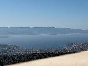A coastal cityscape with mountains in the background, a clear sky, and a view of the sea. - Petit coin de paradis (Alata)