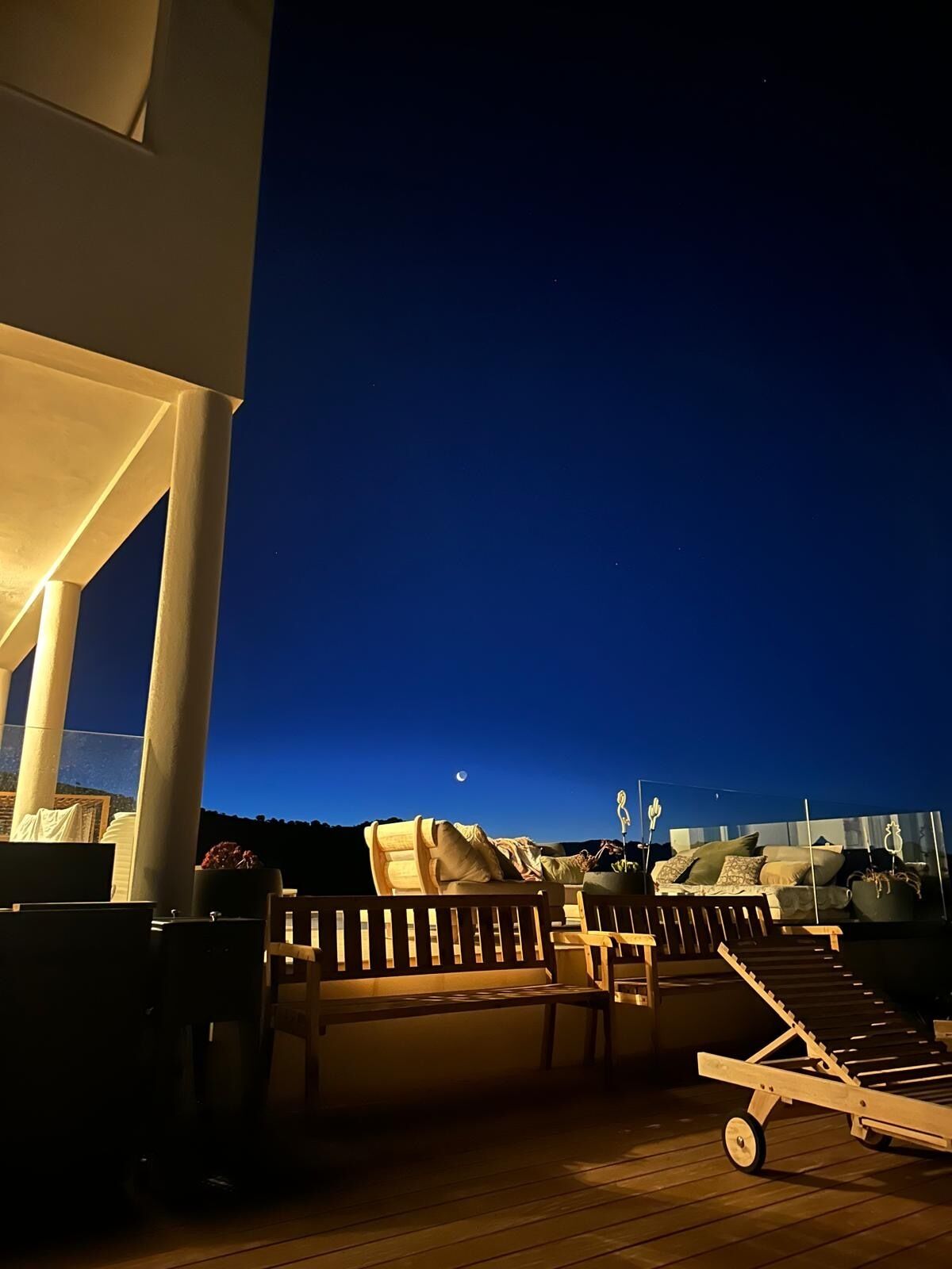 An outdoor deck with lounge chairs, a wooden bench, and a sun lounger.