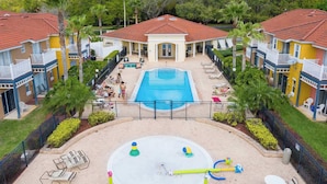 Un complejo residencial con piscina central, varios balcones y un patio cercado con mobiliario exterior.
