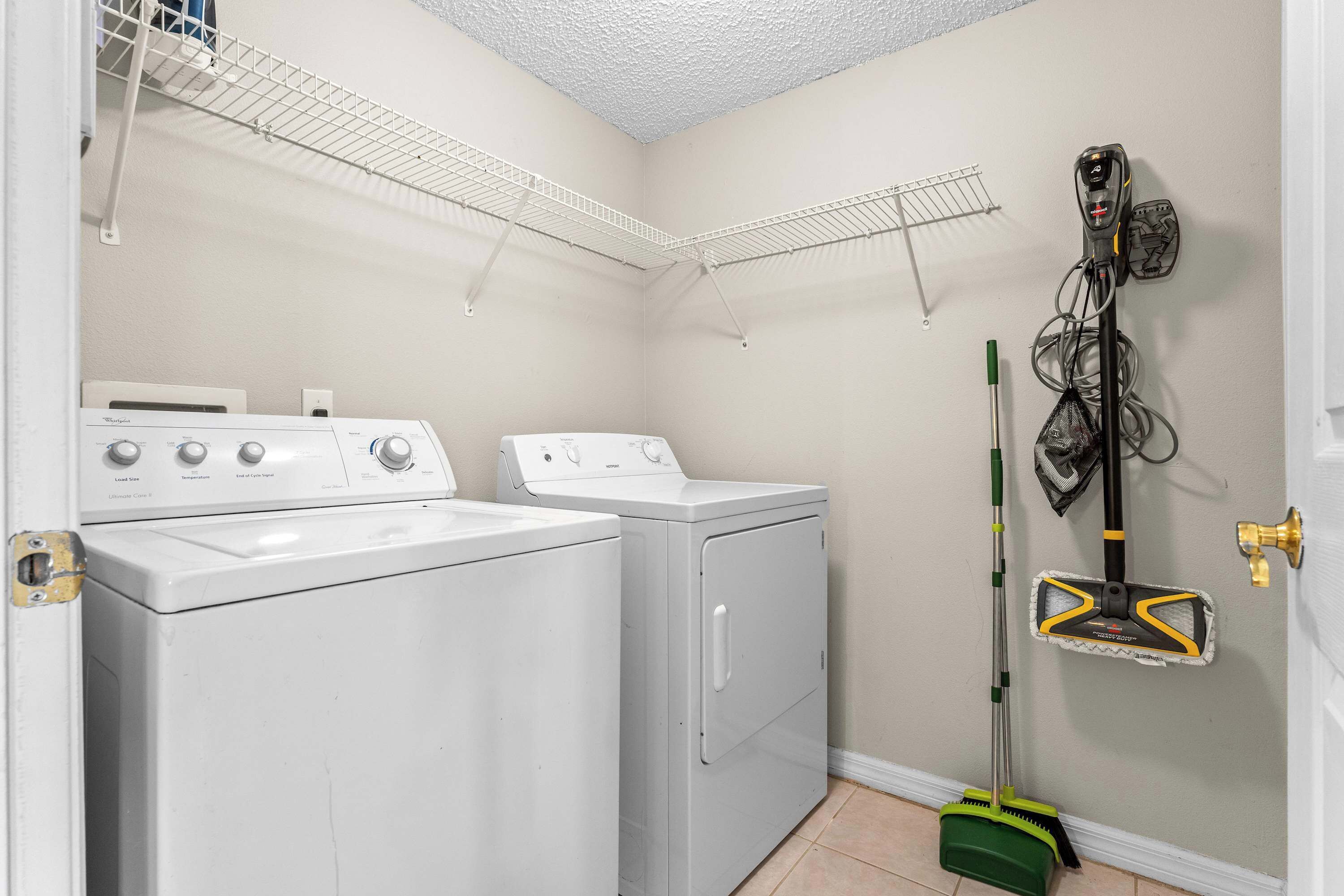 A laundry room with two washing machines, a drying rack, and a vacuum cleaner.