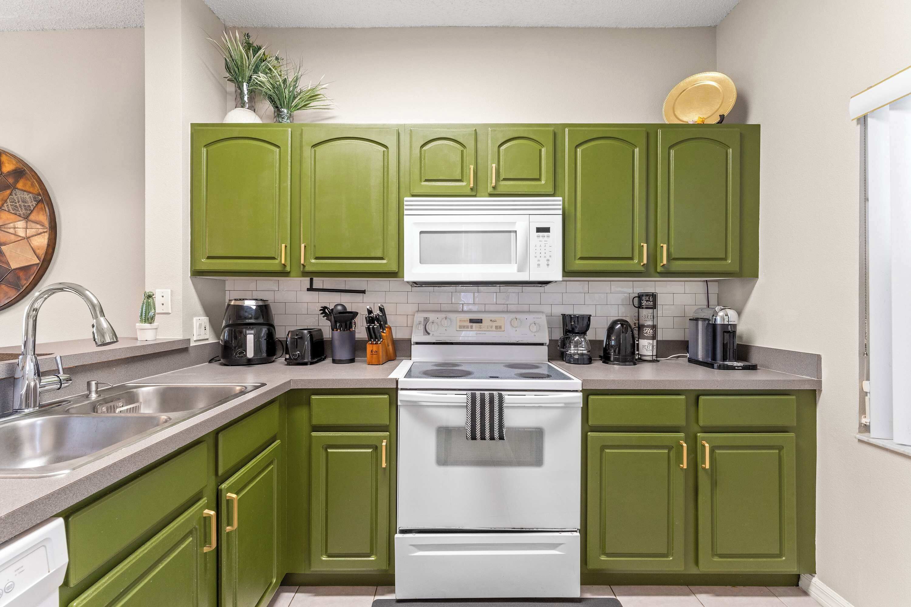 A kitchen with green cabinets, a white stove, and a microwave.