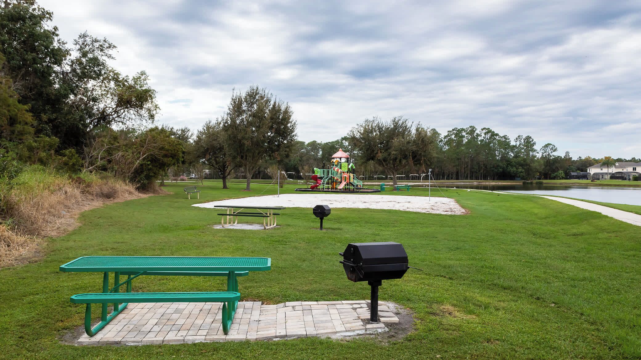 A park with a playground, picnic tables, and a barbecue grill.