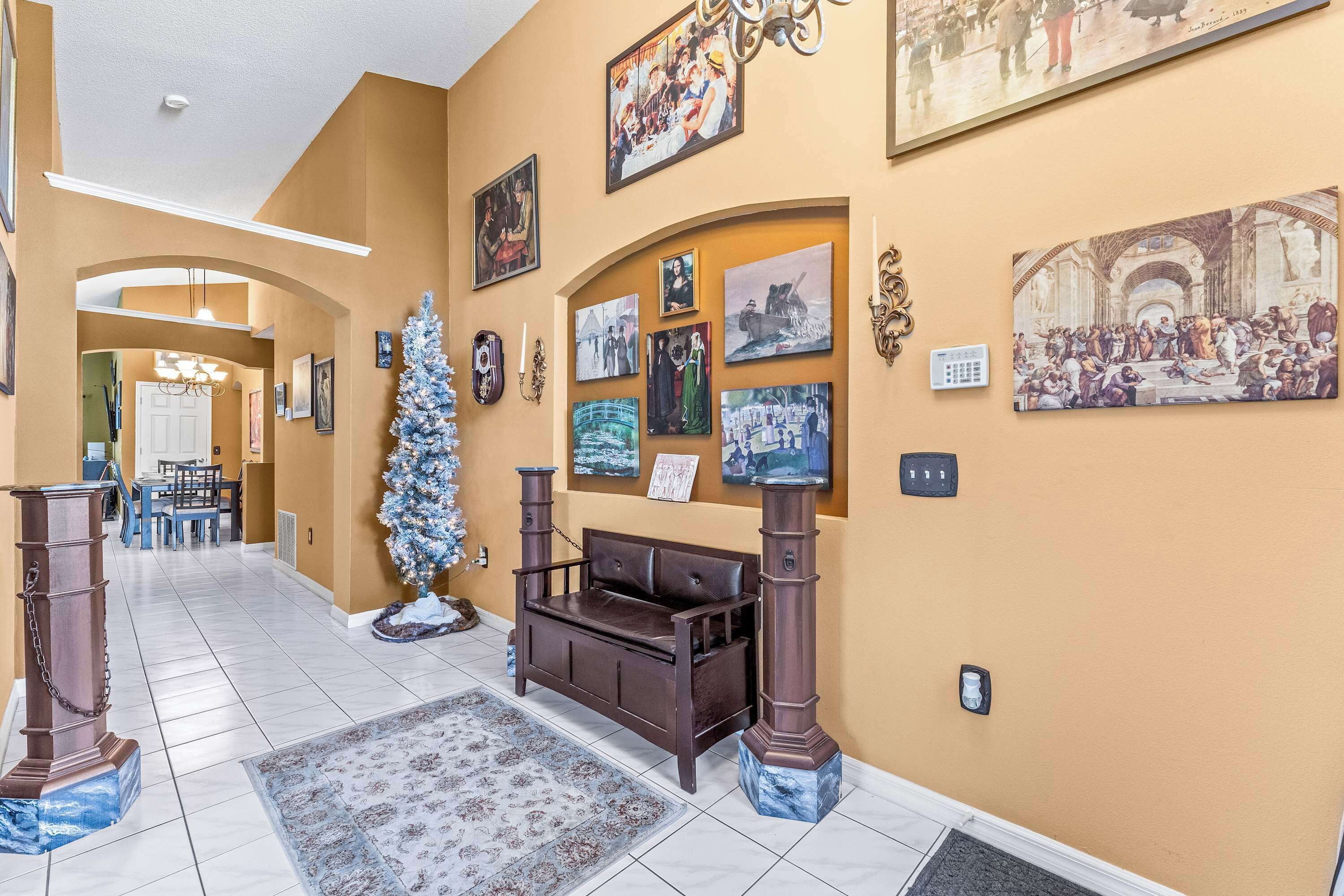 A hallway with a brown sofa, a Christmas tree, and various framed pictures on the walls.