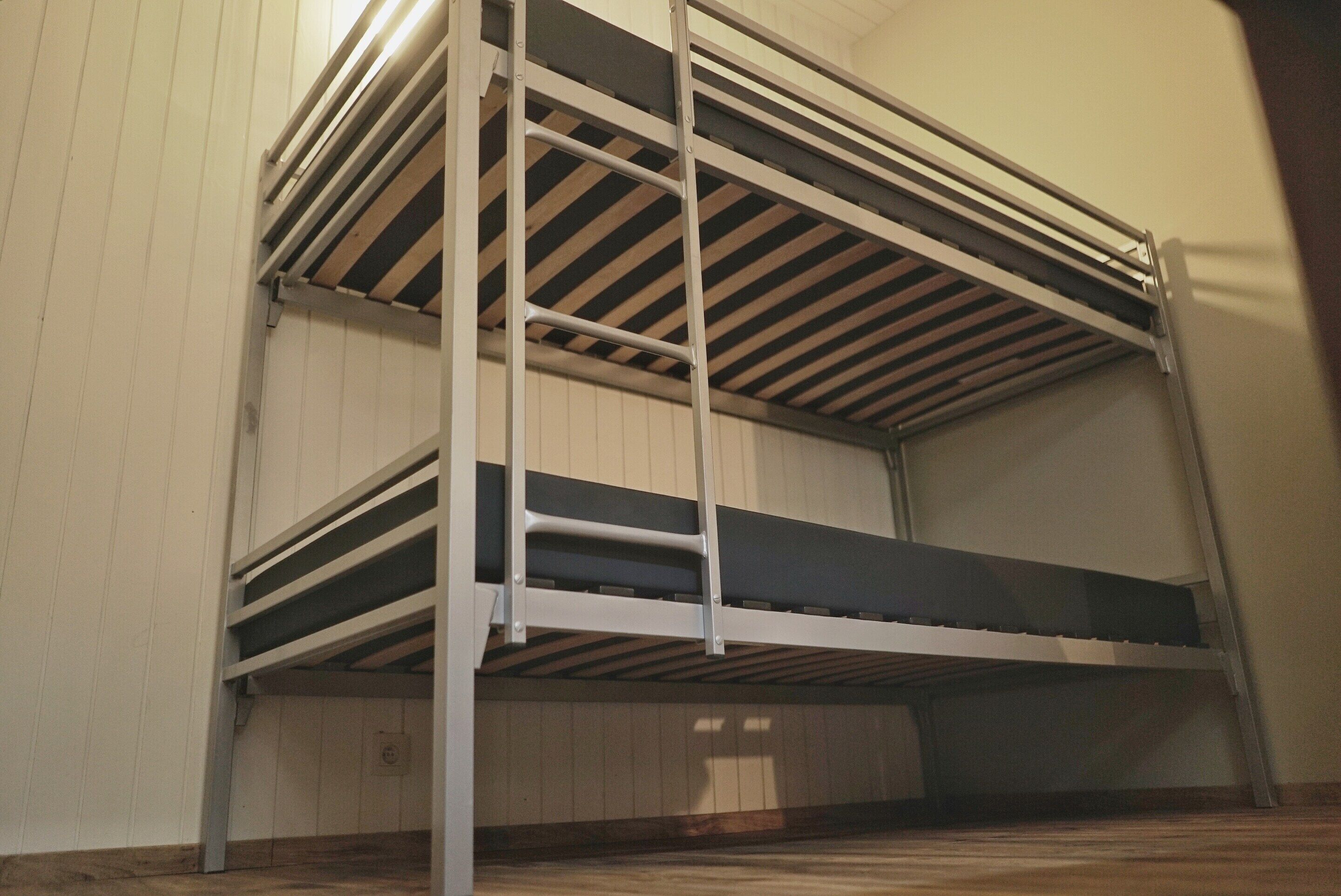 A bunk bed with metal railings and a wooden floor.