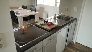Une cuisine moderne équipée d’une cuisinière intégrée, d’un évier et d’un coin repas avec une table et des chaises.