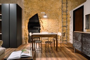 A rustic kitchen with a stone wall, a wooden table, and bar stools. - Hostmate - Milano - Pontaccio - Brera (Milano)