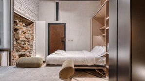 A compact bedroom with a brick wall, a wooden door, a bed with white linens, and a wardrobe. - Hostmate - Milano - Pontaccio - Brera (Milano)