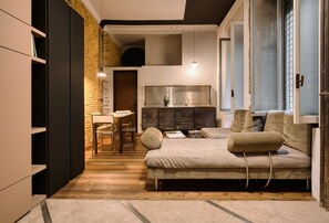 A modern living room with a sofa, a dining area, and a kitchen. - Hostmate - Milano - Pontaccio - Brera (Milano)