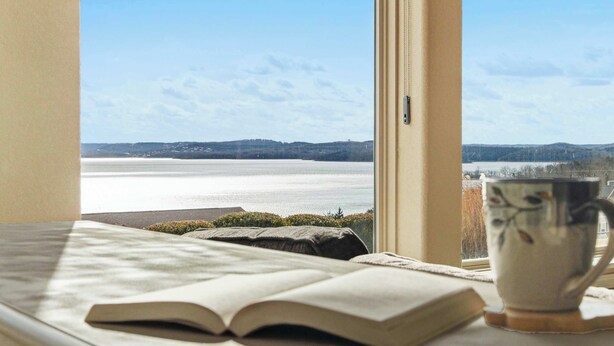 A room with a view of a lake, a book, and a mug on a windowsill. - Majestic Retreat Stay for 6 (Branson)