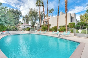 A swimming pool with lounge chairs, surrounded by palm trees and a building with a red roof. - 2 Mi to Dtwn Palm Springs! Modern Condo w/ Pool (Palm Springs)