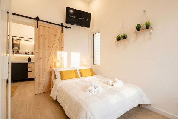 Une chambre à coucher comprenant un lit, une porte coulissante, un téléviseur et des étagères murales ornées de plantes.