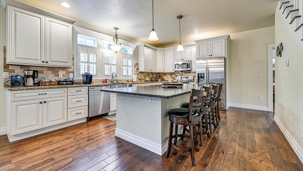 A spacious kitchen with white cabinetry, a large island with bar stools, a microwave, and a refrigerator. - Limpy Creek Access! Family Retreat in Grants Pass (Grants Pass)